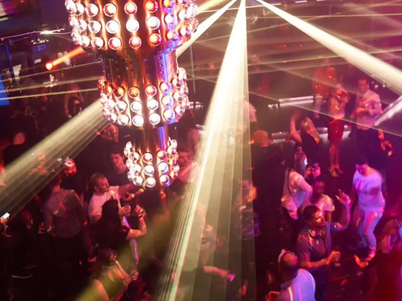 a packed dance floor with bright lighting in the foreground