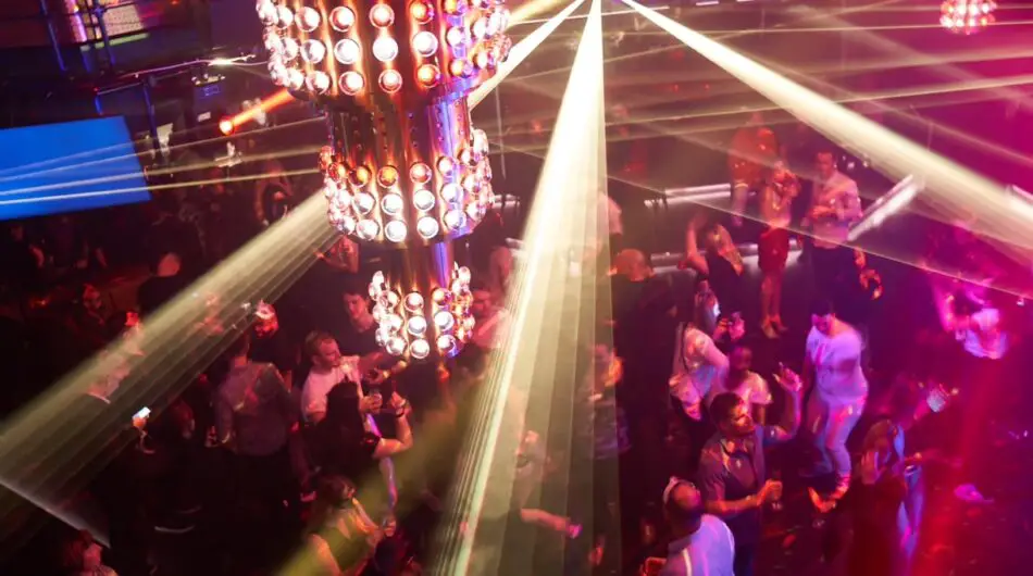 a packed dance floor with bright lighting in the foreground