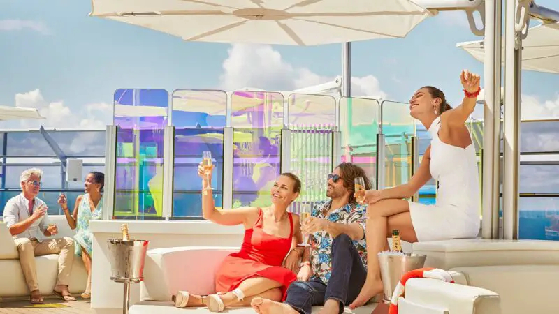 people enjoying a beverage in the sun on a white lounger during Virgin Voyages 'Rockstar' champagne hour
