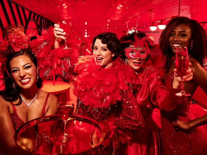 A group of people dressed in red and feather boas drinking alcoholic drinks