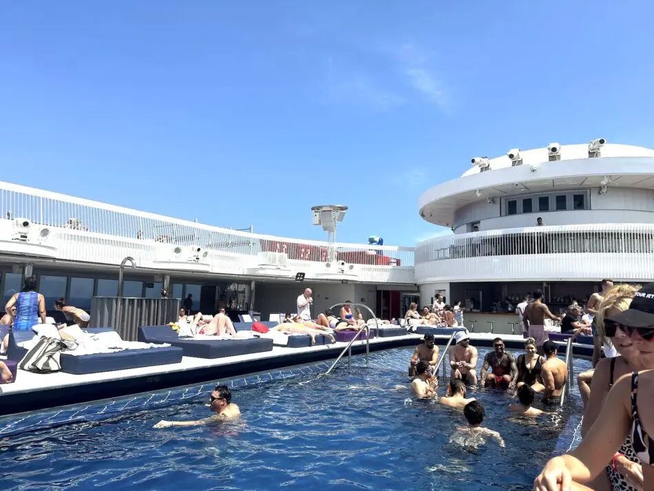 A pool with people around it onboard a Virgin Voyages cruise ship