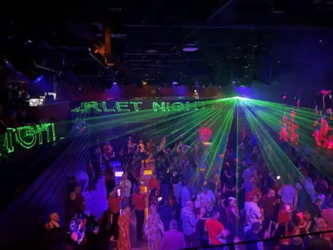 A nightclub with lasers projecting the words 'scarlet night' onto the walls in green lighting