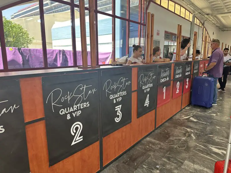 A row of cruise check-in desks labeled 'Rockstar Quarters and VIP'