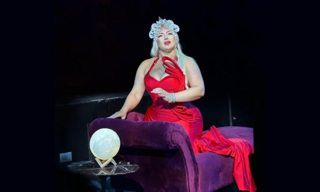 A lady dressed in red sitting on a purple sofa