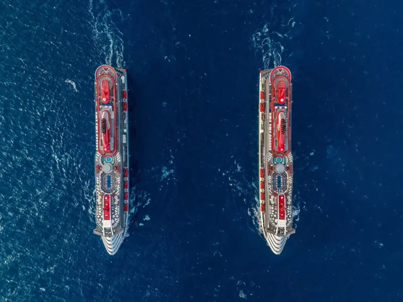 Valiant Lady and Scarlet Lady cruise ships sailing in the ocean side by side