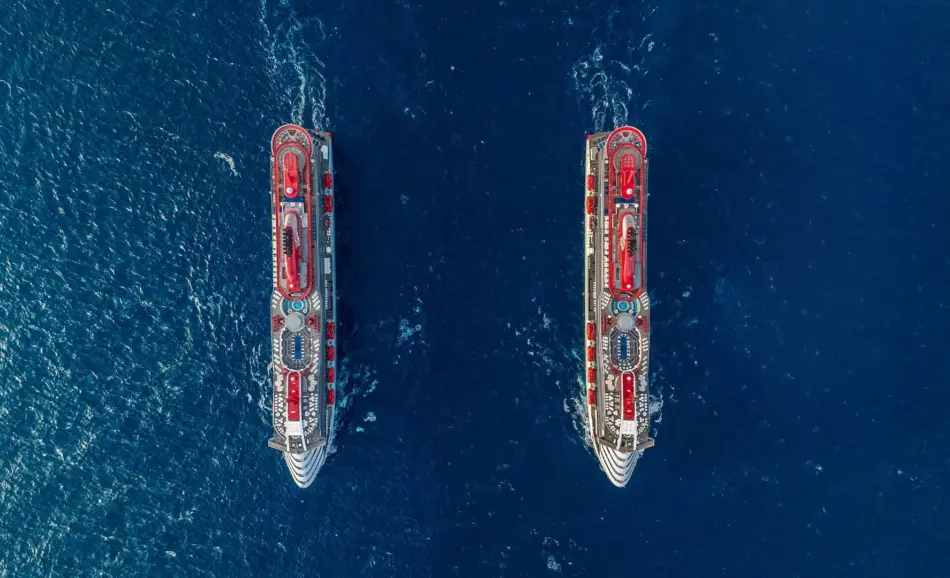 Valiant Lady and Scarlet Lady cruise ships sailing in the ocean side by side