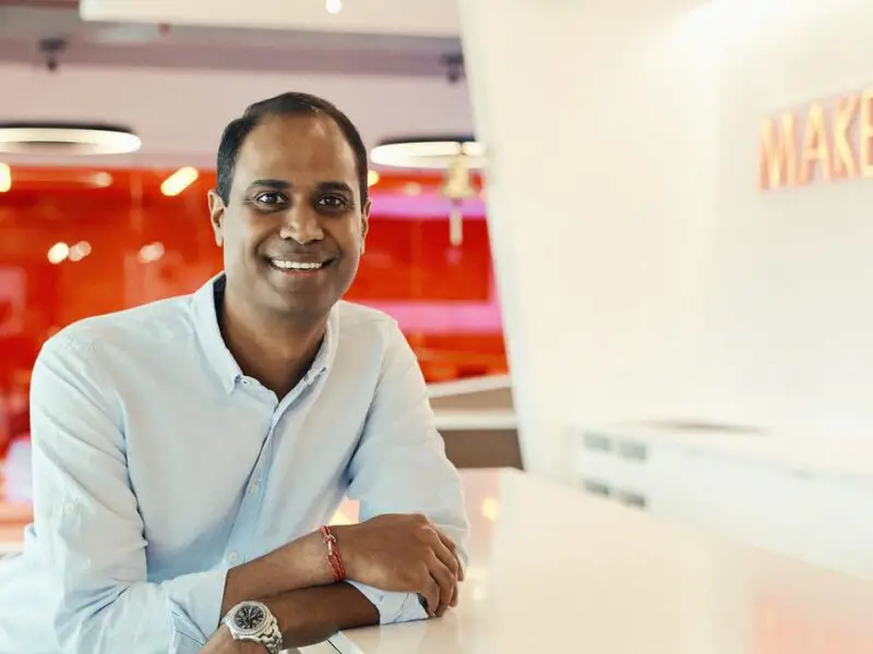 Virgin Voyages CEO Nirmal Saverimuttu sitting against a white and red background