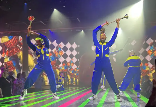 A person holding a trumpet with dancers