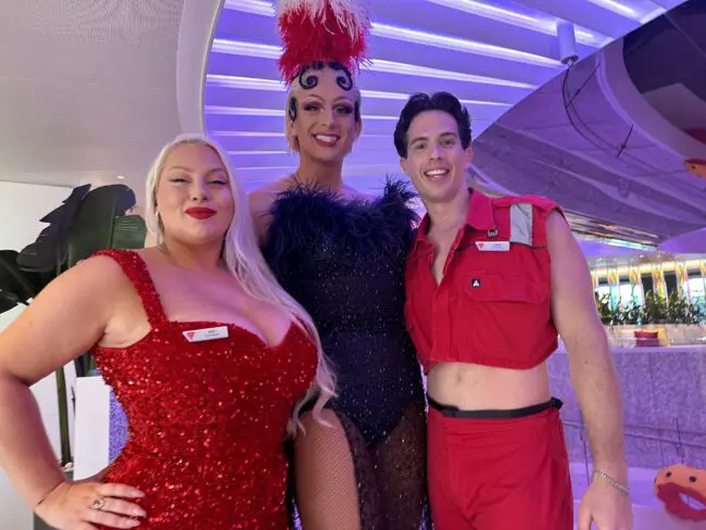 Three cast members in glittering costumes smiling