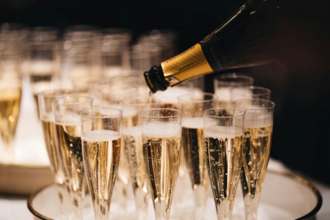 Champagne Flutes filled with champagne with a bottle pouring