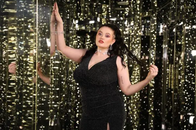 A woman dressed in black on a mirrored hallway