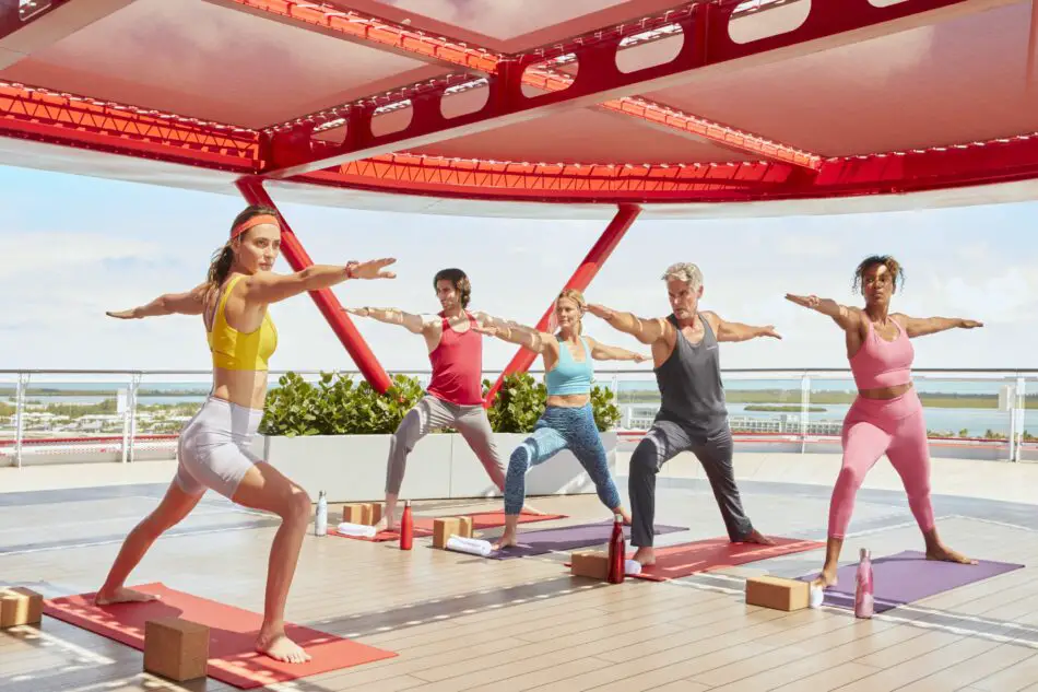 People participate in a group yoga class onboard Scarlet Lady on the Perch. Group fitness classes are included.