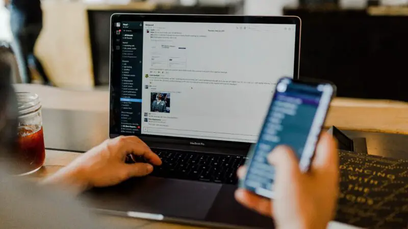 A person working on a laptop and phone using Wi-Fi