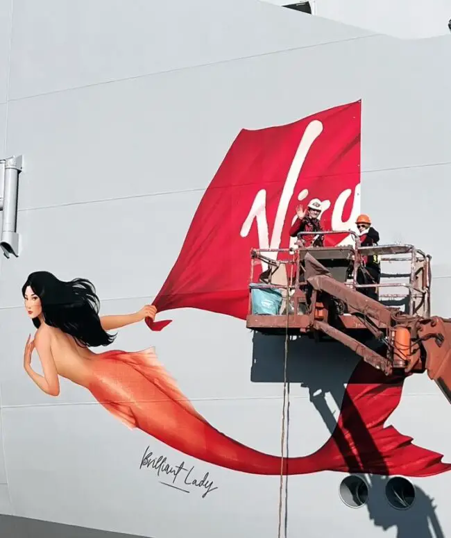 A mermaid being pained on the side of a cruise ship with 'Brilliant Lady' written underneath