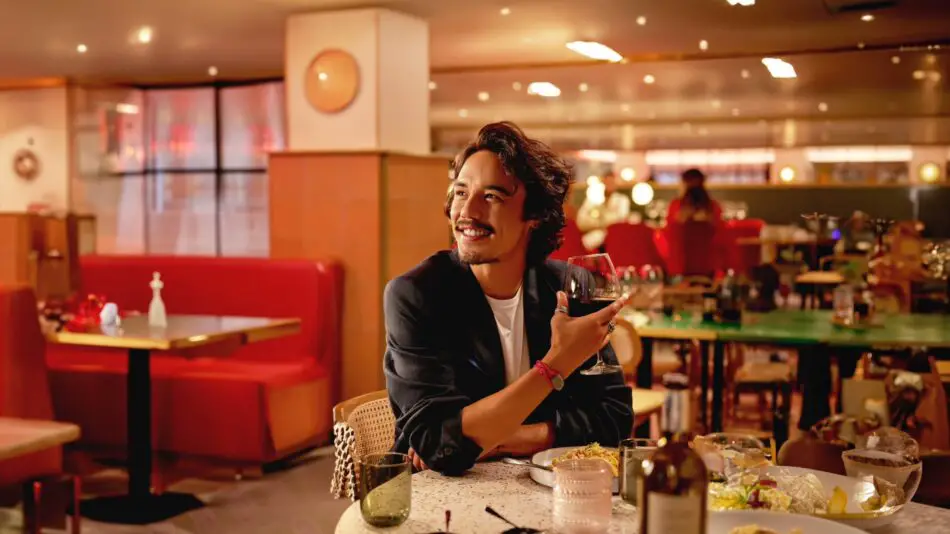 A person, sitting in a restaurant, drinking red wine.