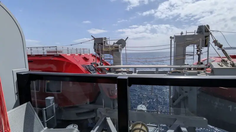 Cruise ship cabin balcony with metal chairs and ocean view