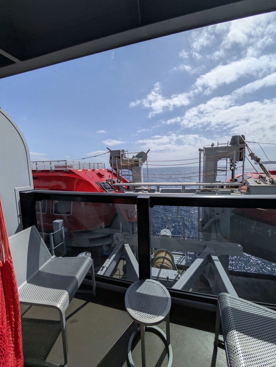Cruise ship cabin balcony with metal chairs and ocean view