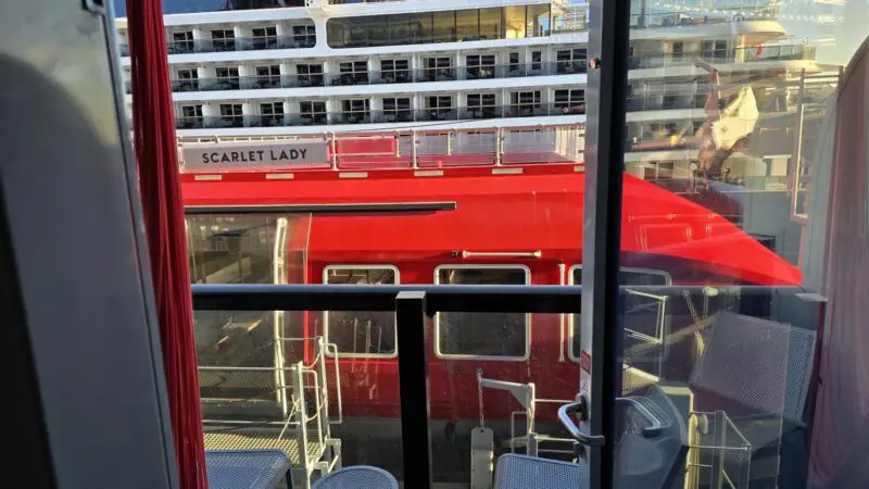 View from a cabin window onto a red Virgin Voyages ship named Scarlet Lady