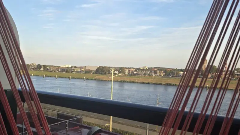 Balcony of a Virgin Voyages cabin with a red hammock and river view