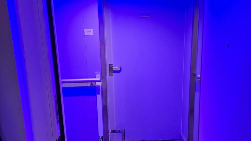 Blue-lit corridor leading to a Virgin Voyages cabin door