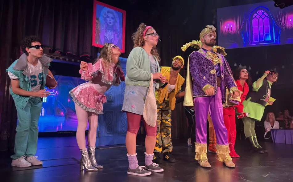 A cast of characters on a colourfully lit stage