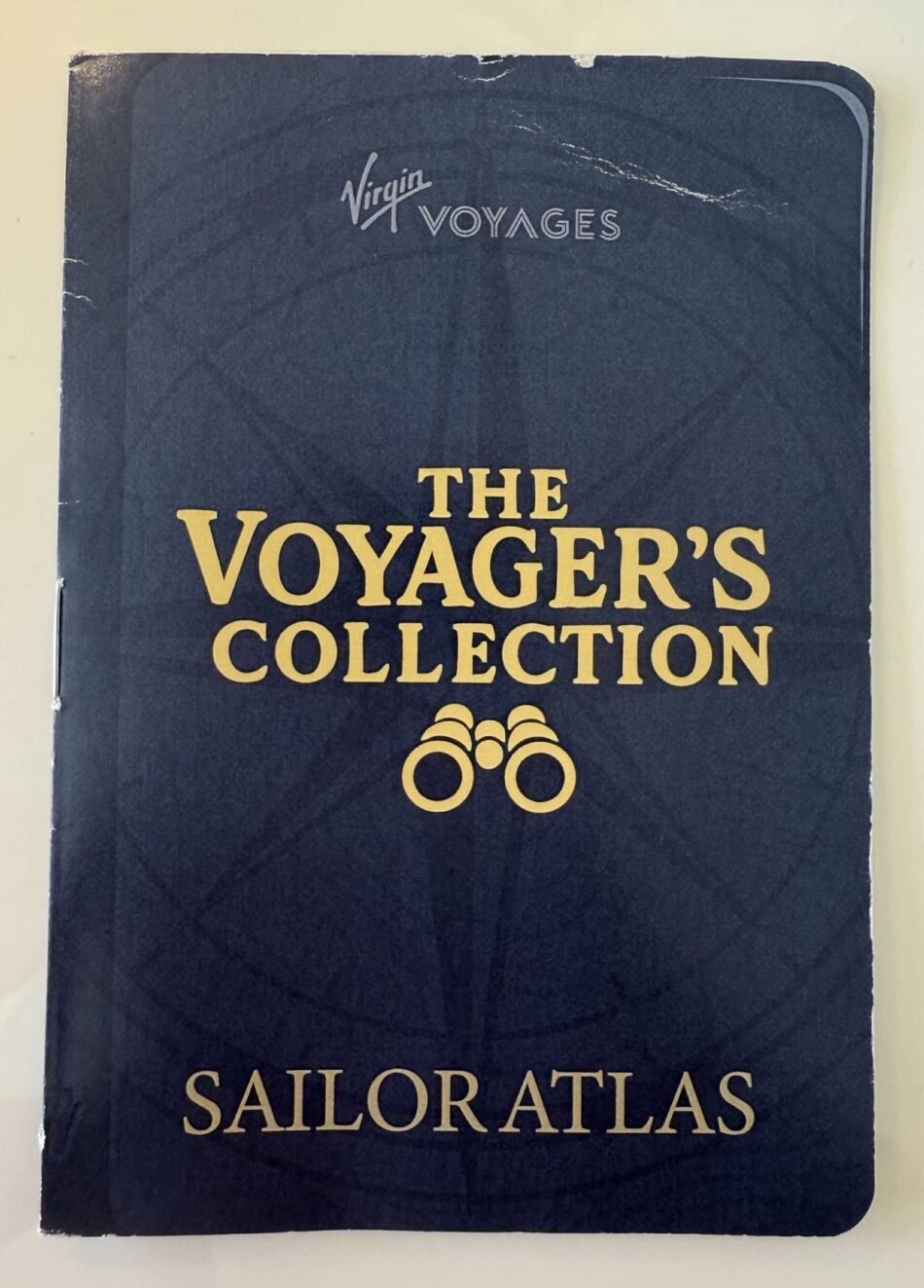 Blue Virgin Voyages Sailor Atlas cover with The Voyager's Collection title and a binoculars graphic