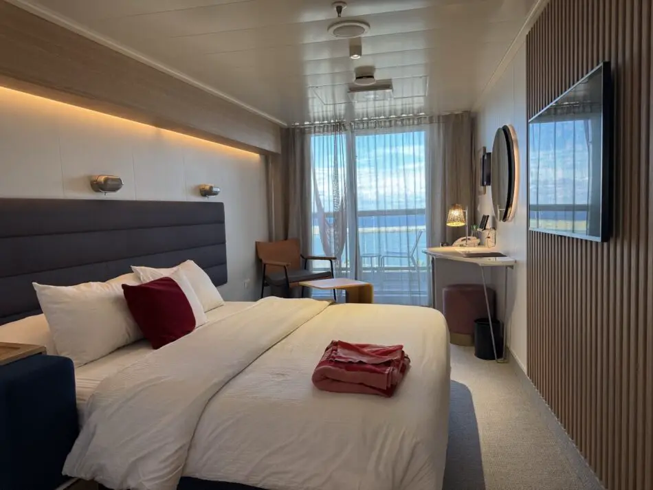 Virgin Voyages cruise ship cabin with a large bed and balcony view