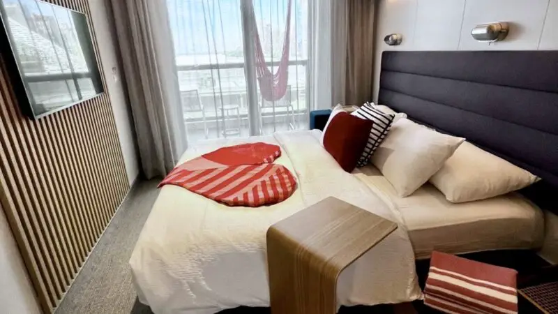 Virgin Voyages cruise ship cabin with balcony and neatly made bed