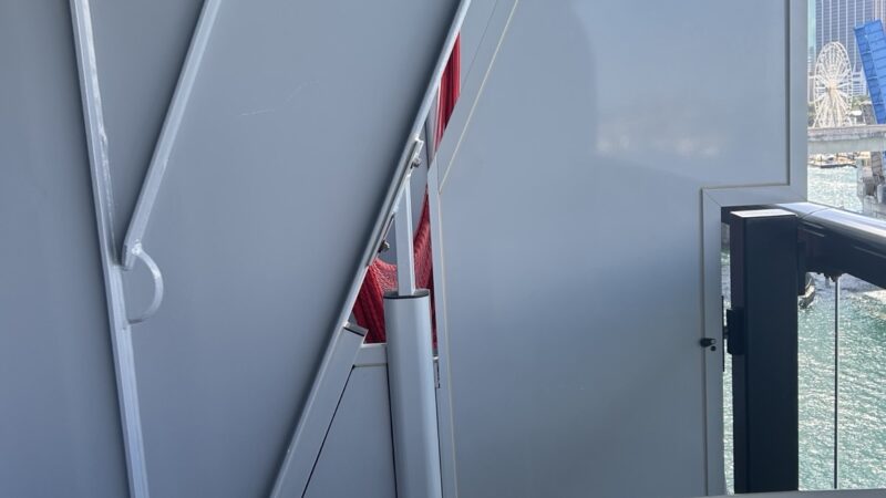 Exterior of a cruise ship cabin with curved metal panels and a glass railing overlooking the water