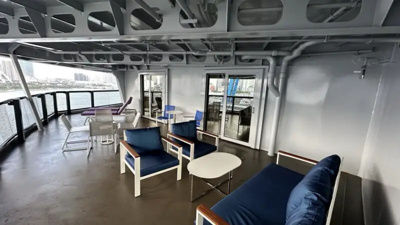 Outdoor lounge on a Virgin Voyages cruise ship deck with blue cushioned seating