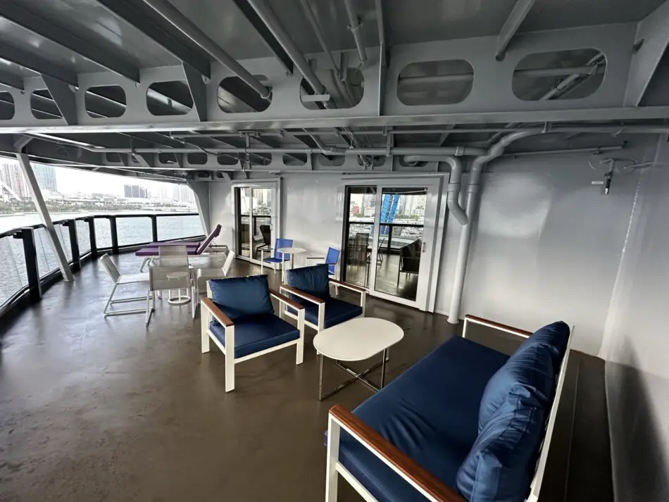 Outdoor lounge on a Virgin Voyages cruise ship deck with blue cushioned seating