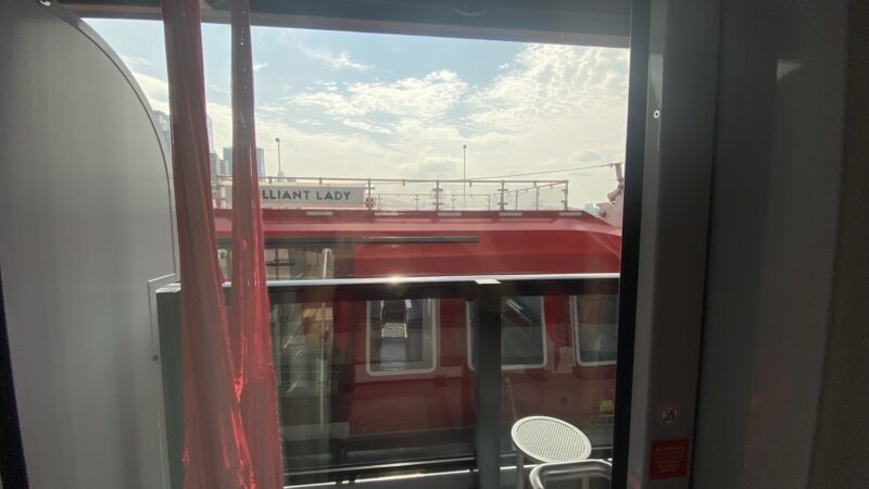 View from a Virgin Voyages cabin balcony onto the red exterior of the ship