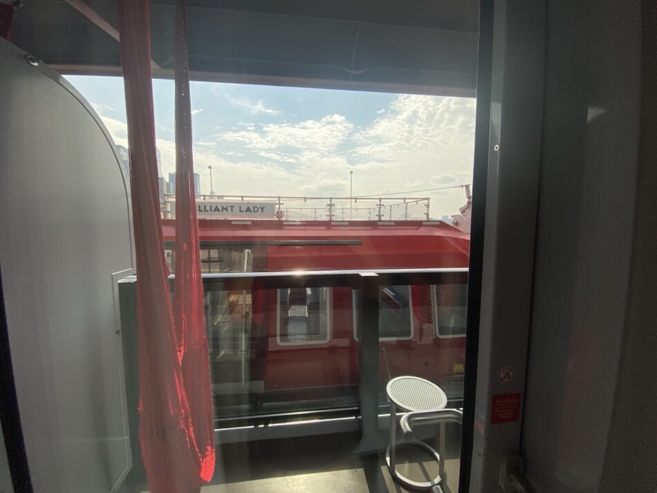 View from a Virgin Voyages cabin balcony onto the red exterior of the ship