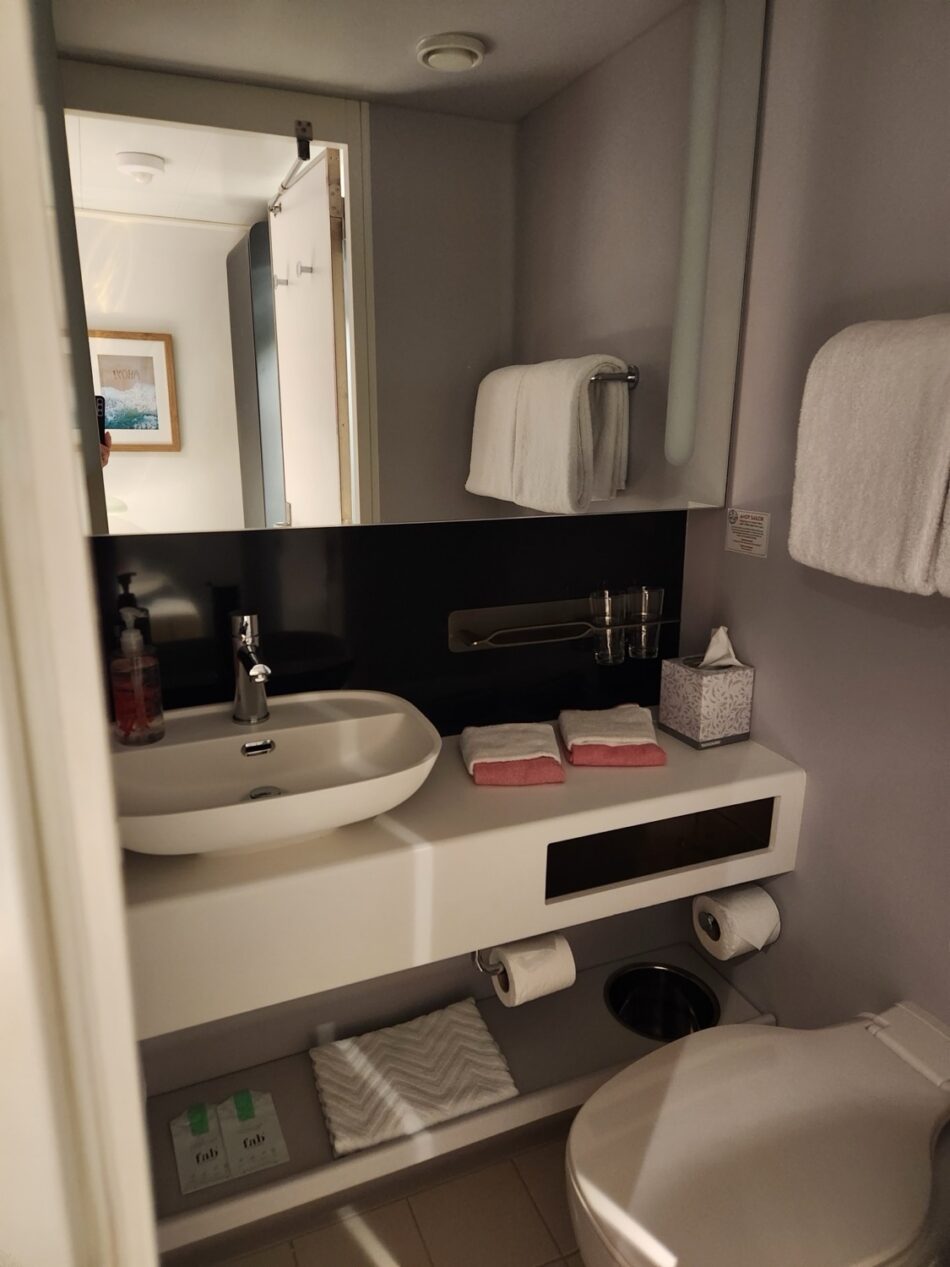 Virgin Voyages cruise ship cabin bathroom with sink, mirror, and towels