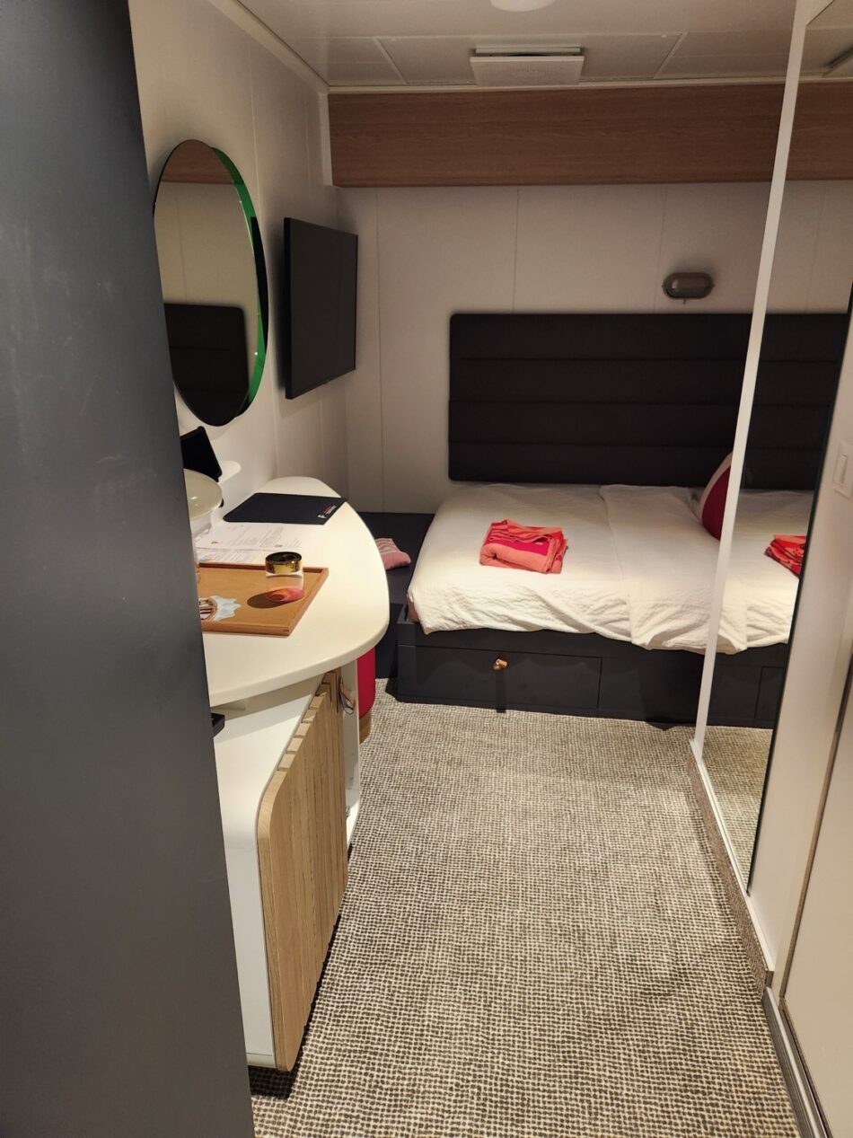 Virgin Voyages cruise ship cabin with bed, desk, and mirror
