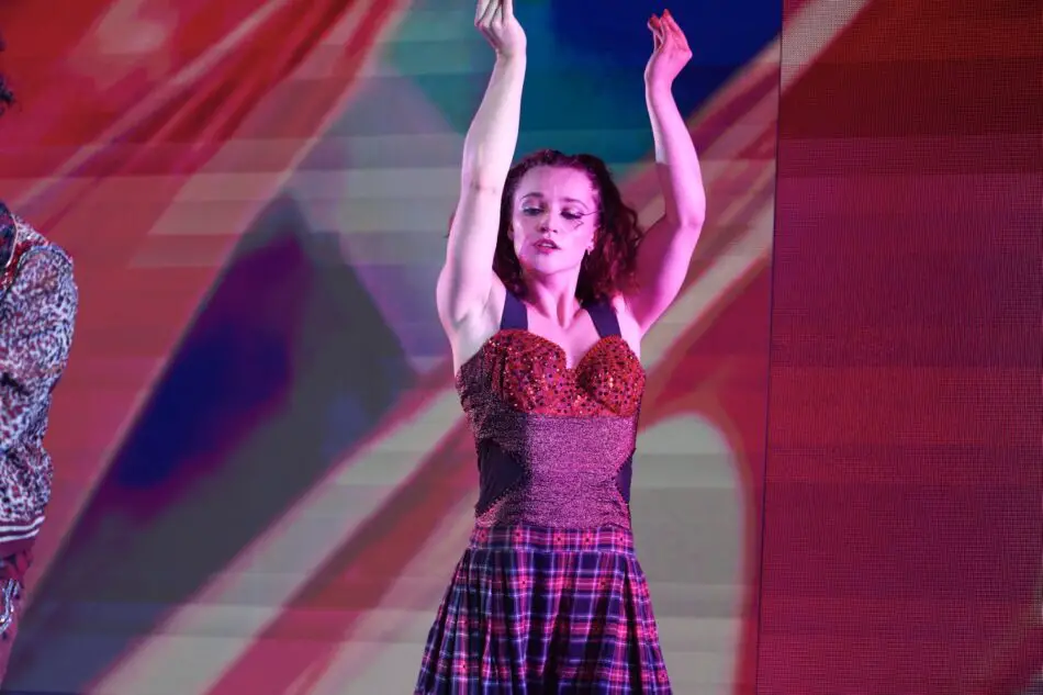 Dancer in red sequined top and plaid skirt performs on stage