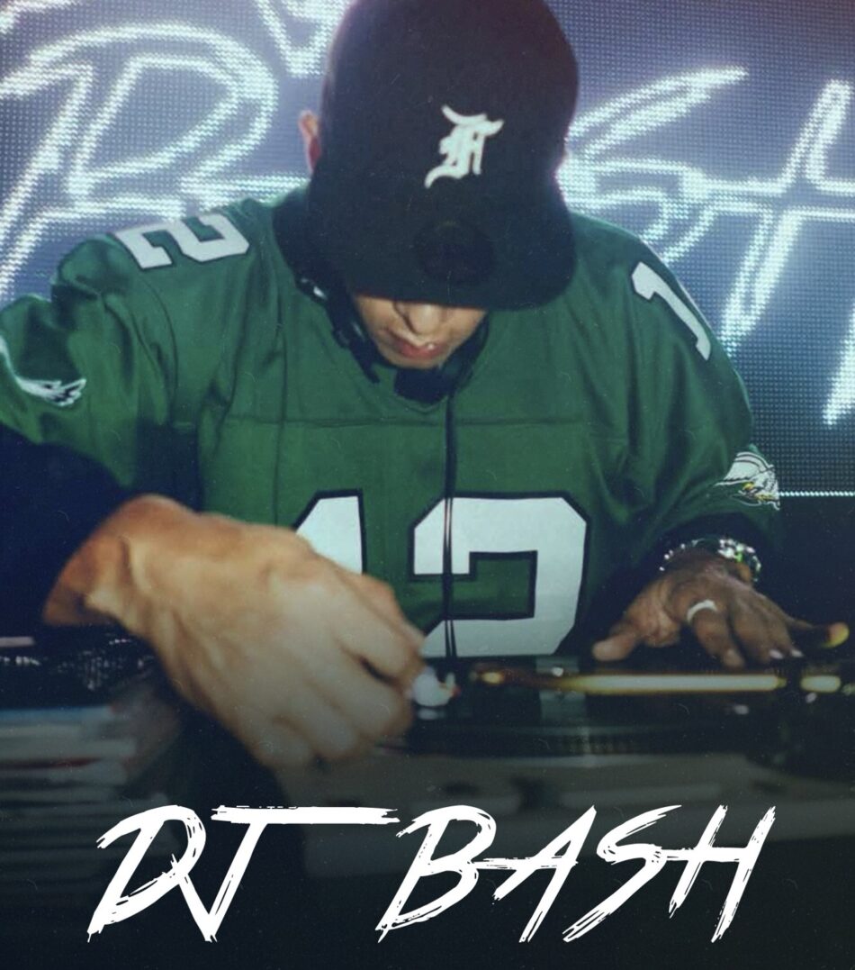 DJ wearing a green jersey and cap spins on turntables on stage