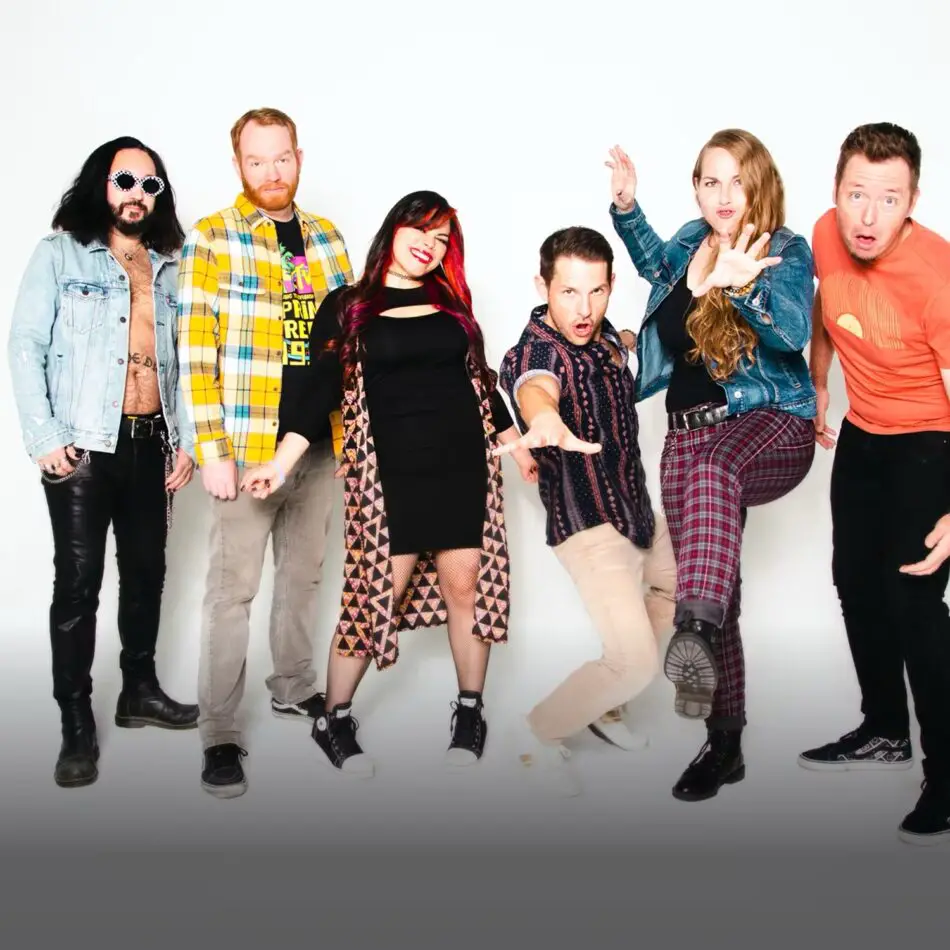 Six people pose playfully in casual outfits against a white studio backdrop