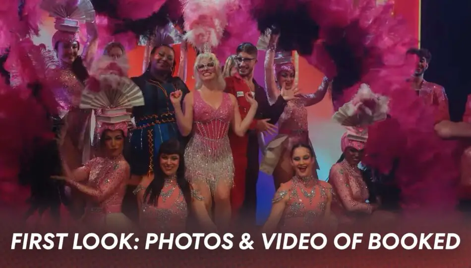 Group of performers in pink sequined outfits performing on a stage with feather props