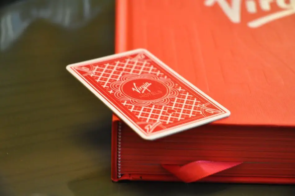 Red playing card-style hotel key on top of a red Virgin-branded book