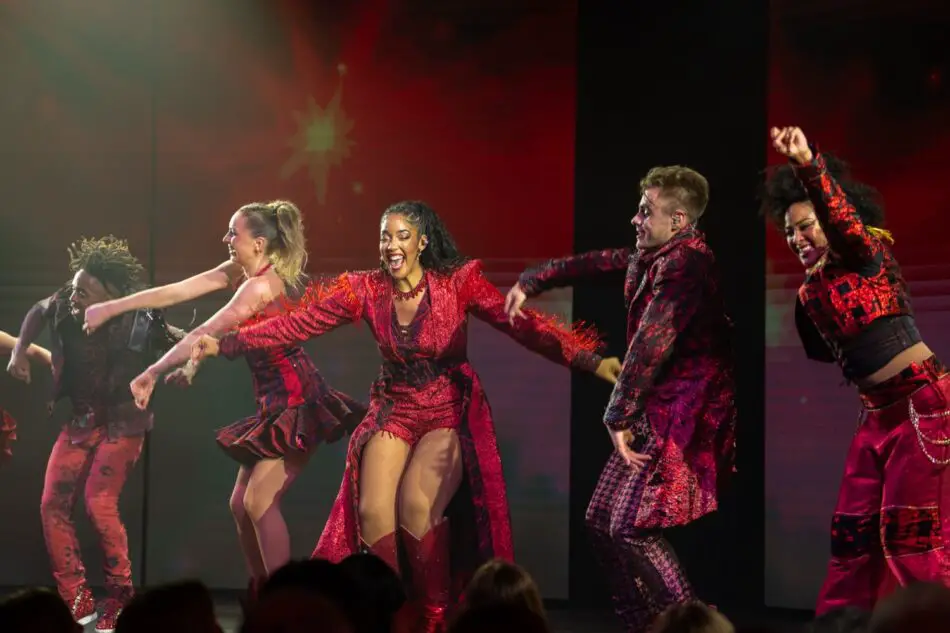Dancers in red costumes perform on stage aboard a Virgin Voyages cruise ship