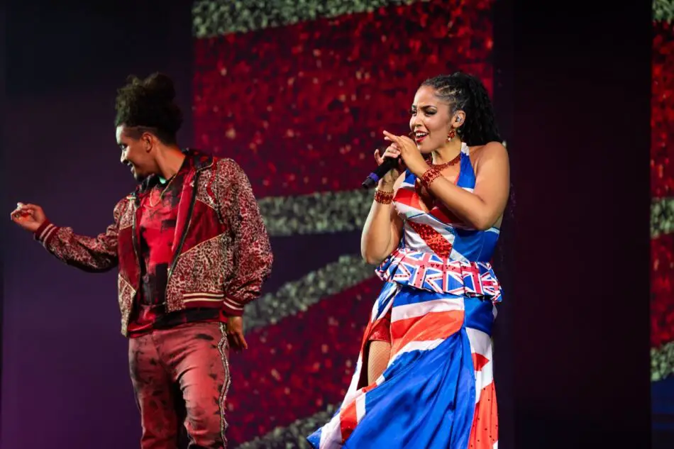 Two performers on stage, a singer in Union Jack dress with microphone
