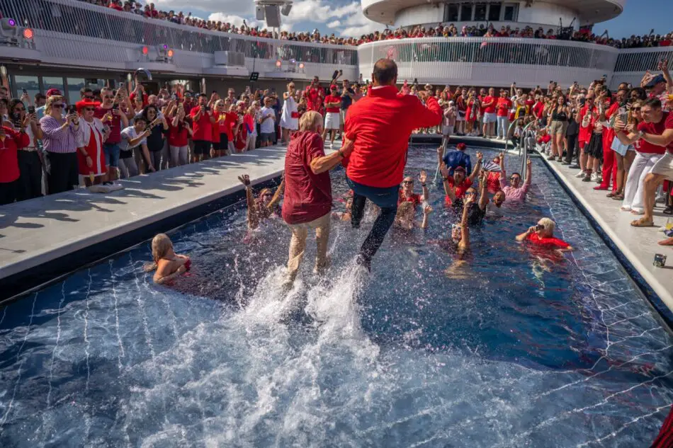 Guests jump into the pool on a Virgin Voyages cruise ship as the crowd cheers