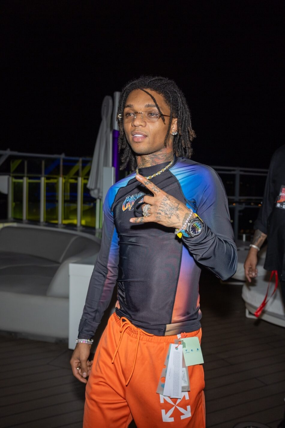 Man with dreadlocks on a Virgin Voyages cruise ship deck at night