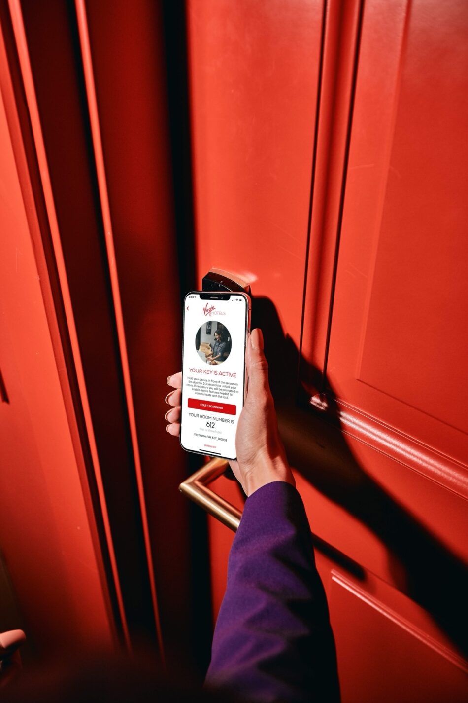 Person holding a phone to a red door at Virgin Hotels London Shoreditch