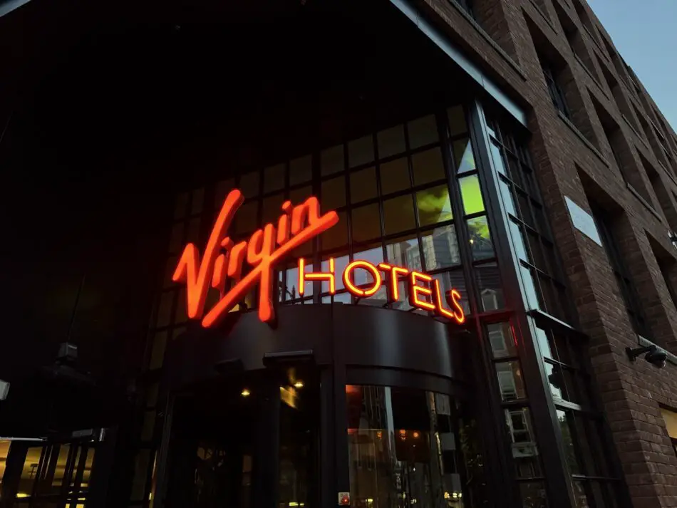 Exterior of a Virgin Hotels building with red neon sign on brick facade