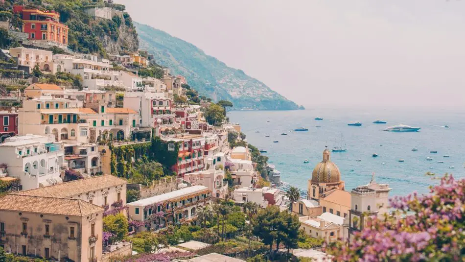Colorful hillside Italian town along the coast with pastel buildings and a domed church overlooking the sea