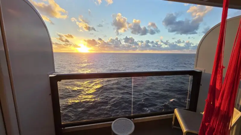 Sunset over the ocean from a Virgin Voyages cruise ship balcony