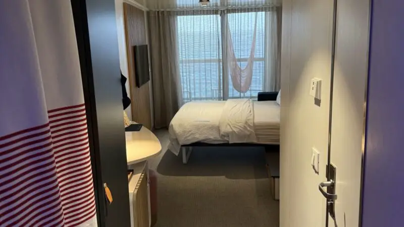 Virgin Voyages cabin with bed, window and hammock