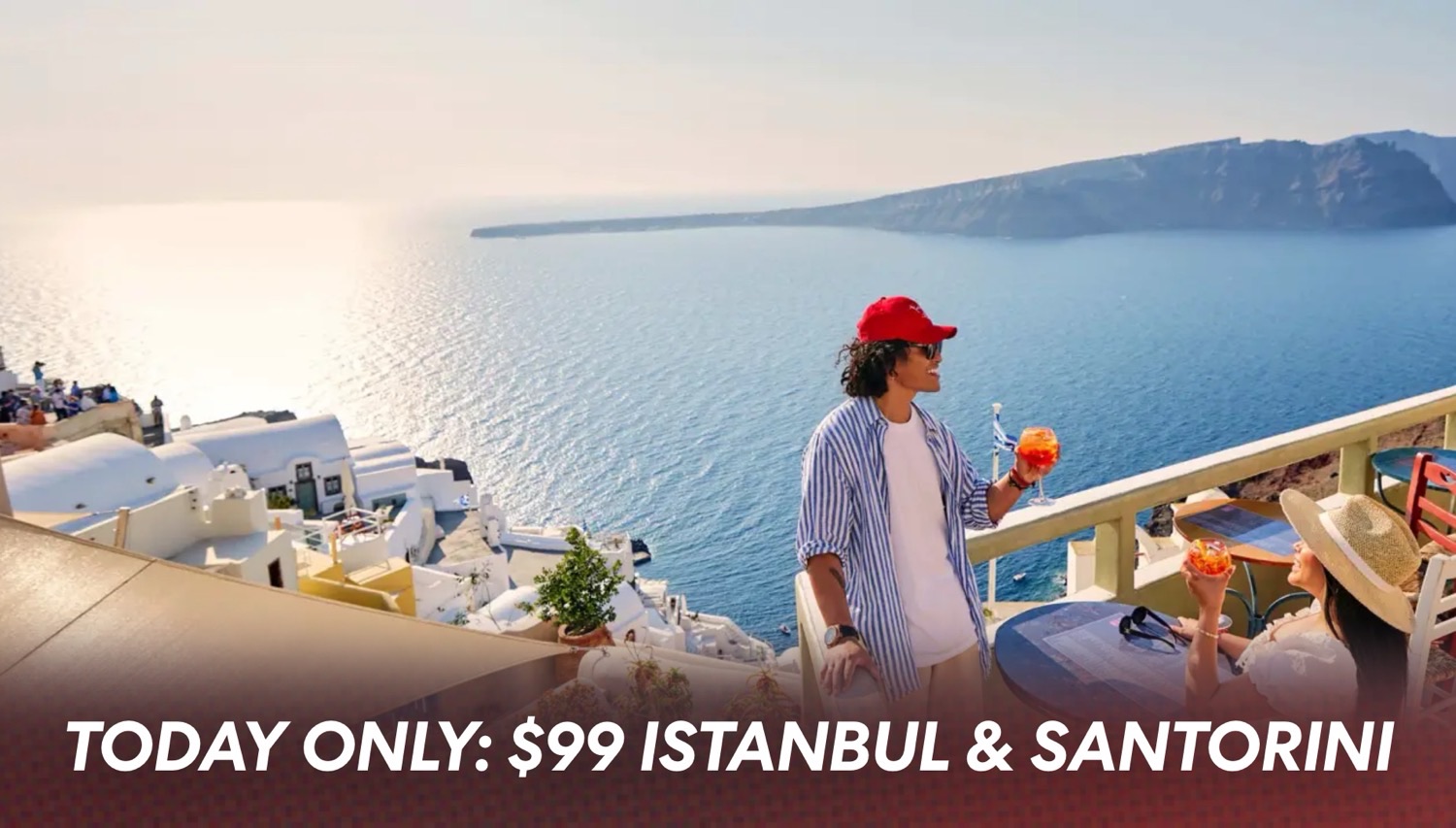 Two people on a Virgin Voyages cruise ship terrace enjoying colorful drinks with Santorini coastline in the background